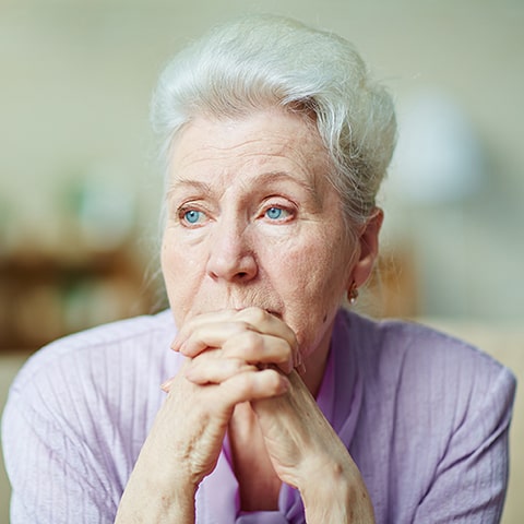 Femme âgée réfléchissant aux traitements disponibles pour la maladie d'Alzheimer en Belgique, incluant médicaments et thérapies.