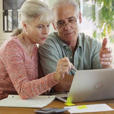  Photo d’une personne âgée consultant ses finances avec l’aide d’un proche, représentant la gestion du montant de l’APA.
